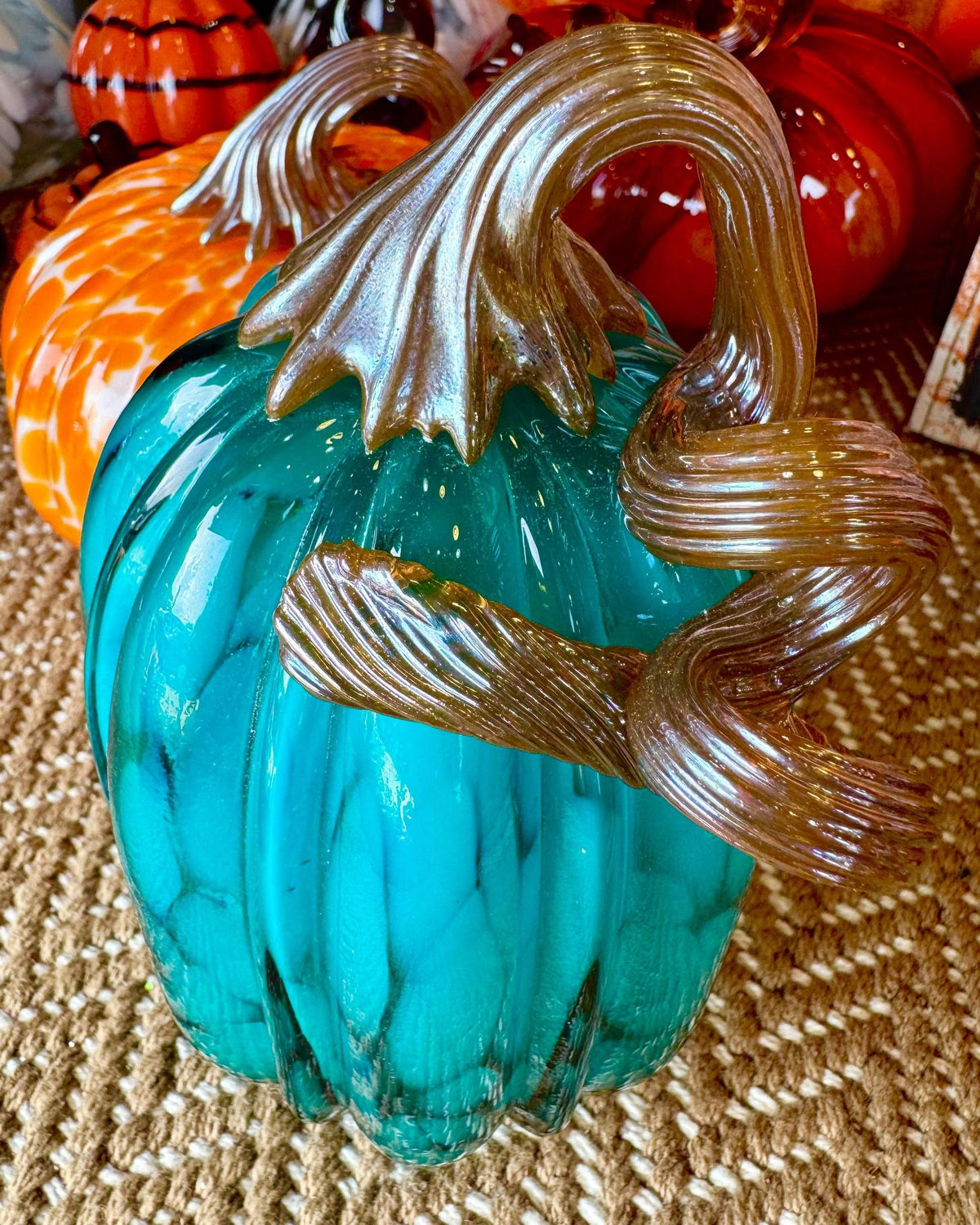 Handblown glass pumpkin in turquoise with metallic toned glass stem in a free flow twist.