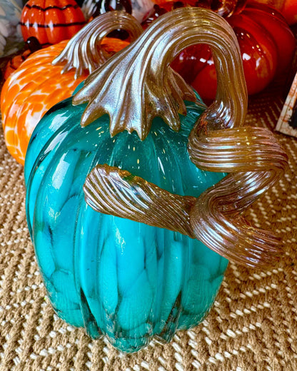 Handblown glass pumpkin in turquoise with metallic toned glass stem in a free flow twist.