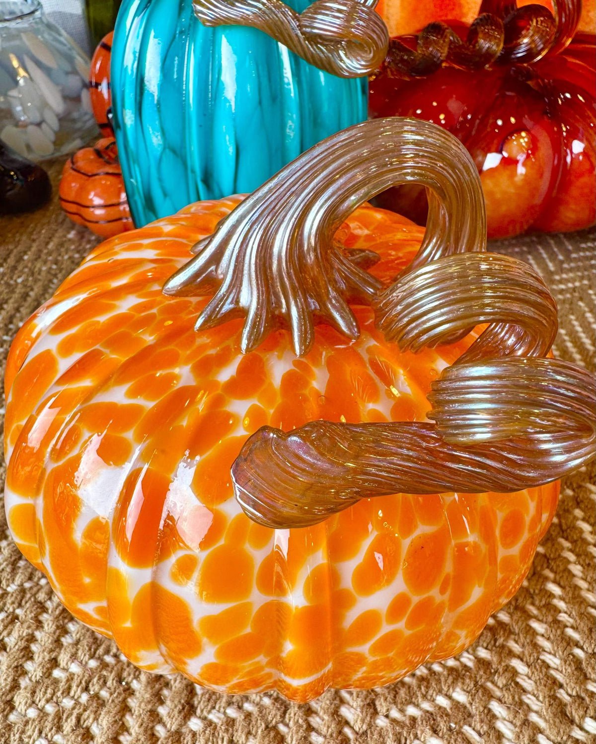Handblown glass pumpkin up close in orange and white with silver stem accent.