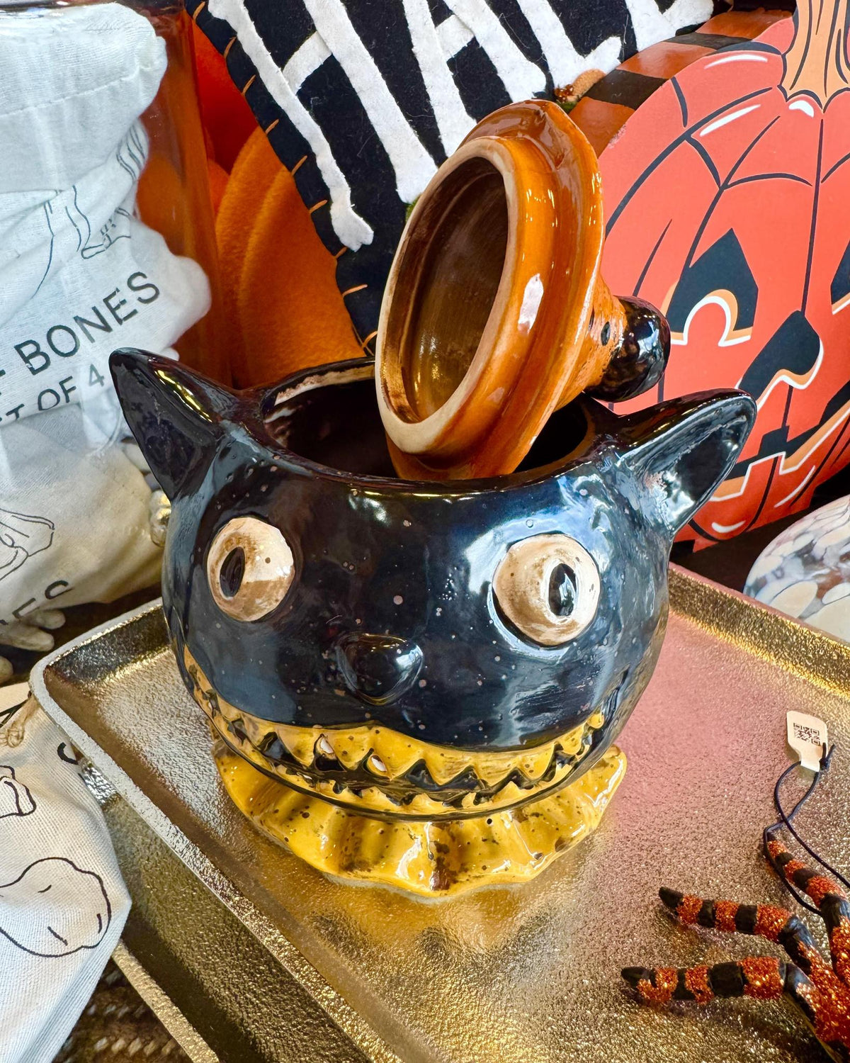 A ceramic Halloween lidded jar shaped like a black cat wearing an orange witch hat.